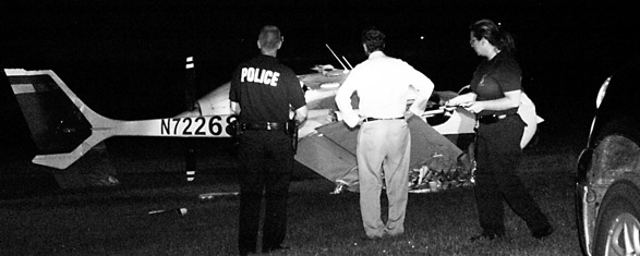 Dr. Charles Graper looks on as police investigate the scene where he crashed his mult-engine Cessna Thursday evening